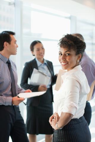 Woman looking at camera while coworkers work in the background. 